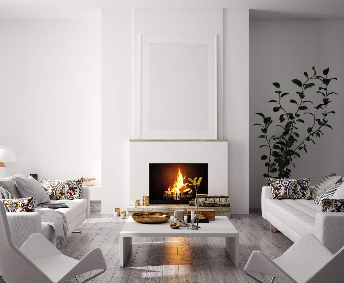 Bright white lounge with a lit fireplace, two white sofas, a low coffee table and pale timber floorboards